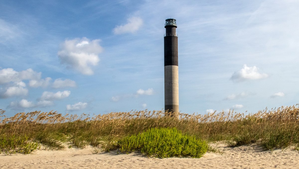 Beach and sea oats with Oak Island Lighthouse in background.