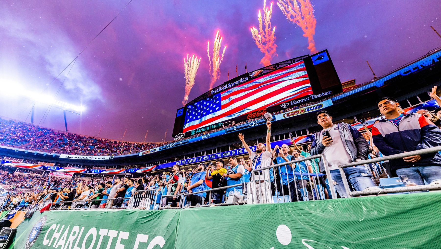 Stadium full of fans cheering on Charlotte FC with fireworks popping off above scoreboard.