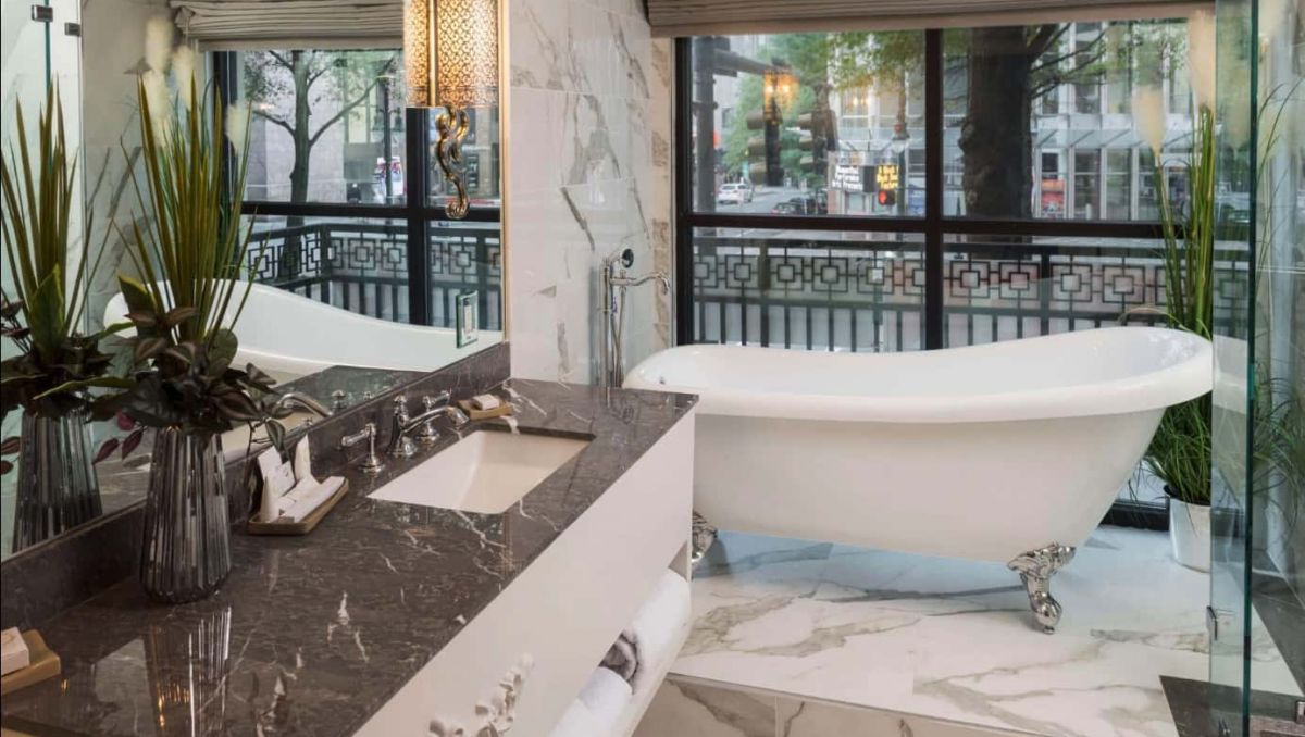 Interior shot of clawfoot tub with city buildings peeking through window
