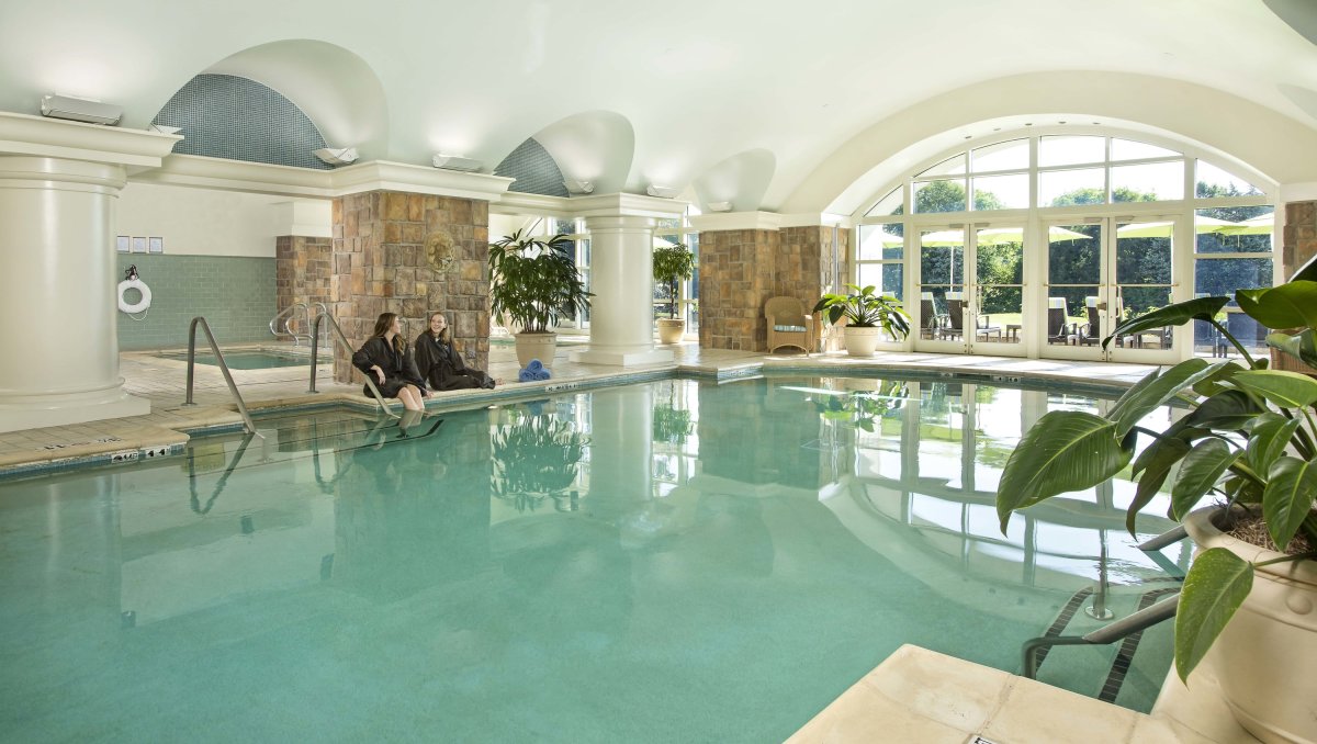 Two women sitting on edge of indoor pool at a spa